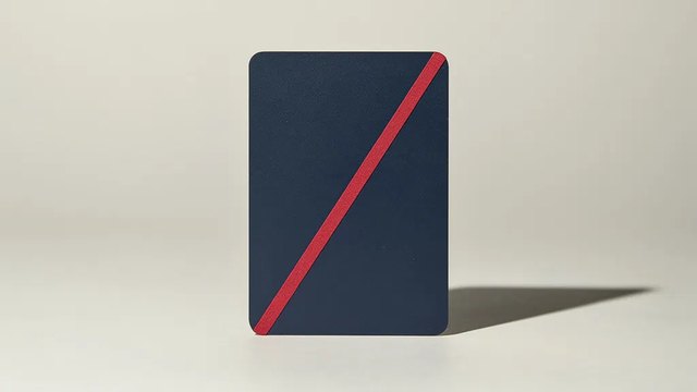 A blank matte navy card standing upright on a pale grey surface, with a single red stripe running diagonally across it.