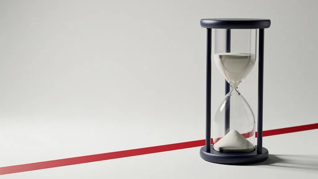 A navy hourglass on a pale studio floor with a red stripe running diagonally behind it.
